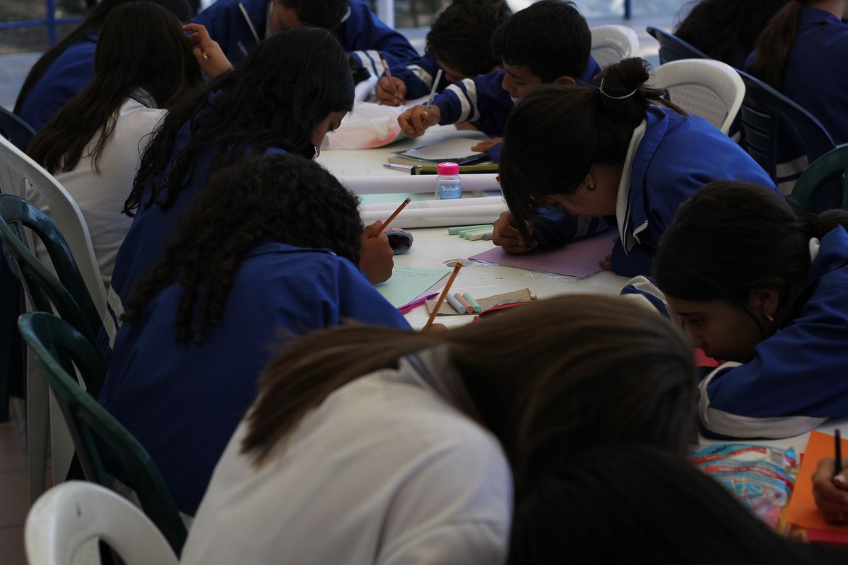 Estudiantes con uniforme escriben en sus cuadernos durante un taller