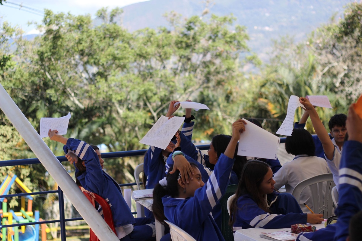 Estudiantes levantan las hojas con los textos que escribieron