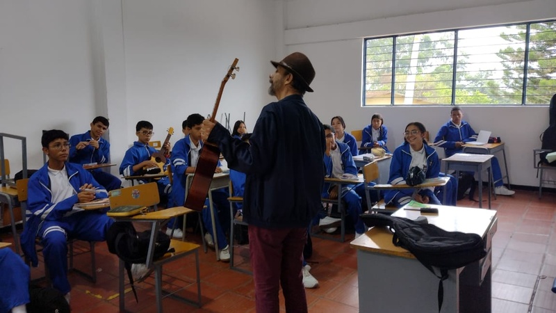 Un tallerista con guitarra frente a estudiantes de grado noveno